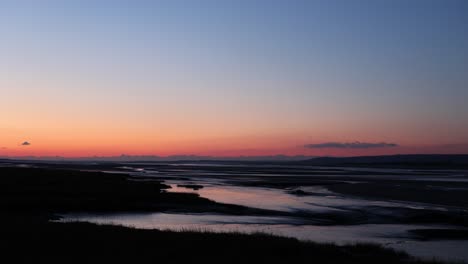 50-frames-per-second-shot-of-a-winter-sunset-sky-over-an-estuary,-with-a-small-shipwreck-on-the-bank