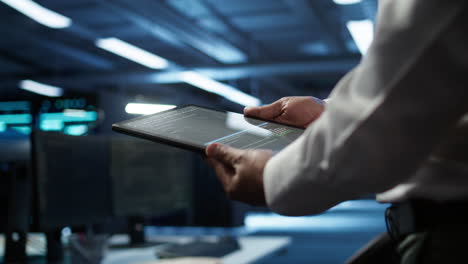 Close-up-of-tablet-used-by-IT-worker-doing-maintenance-on-server-farm-gear