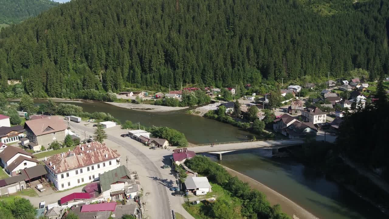 Aerial view of a village nestled between a river and a forest