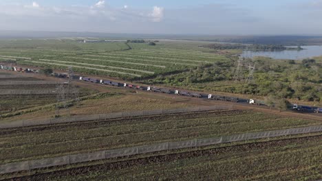 aerial orbit of a huge number of cargo trucks stuck in a long queue on a highway before a border post
