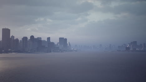 dramatic skyline silhouette of a city along the water on an overcast day