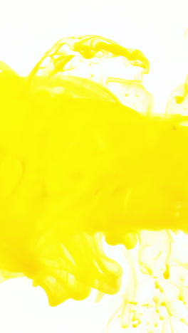 bright yellow paint splashing on white background. a vibrant yellow paint splashes across a clean white surface, creating dynamic textures and patterns. vertical video