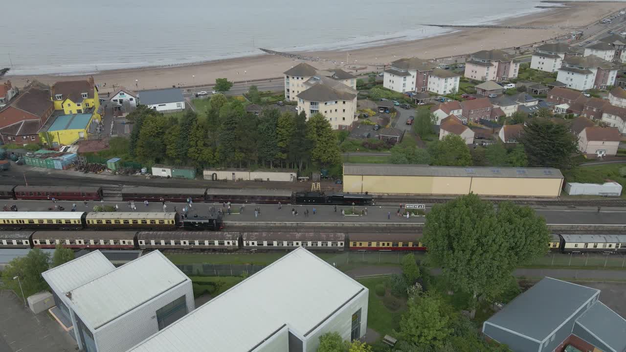 Aerial view of the Minehead steam railway station England's longest heritage line, running 20 miles between Minehead and Bishops Lydeard. Drone moving to right with Minehead beach on the background