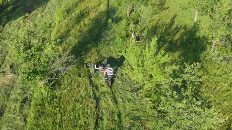 aerial tracking shot over worker cutting grass with mower