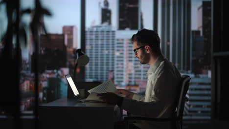 Retrato-De-Un-Hombre-De-Negocios-Exitoso-Y-Reflexivo-Que-Trabaja-En-Una-Computadora-Portátil-En-Su-Oficina-De-La-Gran-Ciudad-Por-La-Noche.-Carismático-Emprendedor-Digital-Realiza-Análisis-De-Datos-Para-Estrategia-De-Comercio-Electrónico.