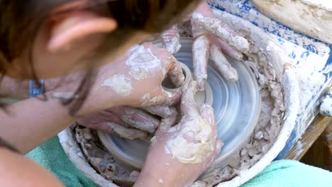 hands of the master potter and vase of clay on the potter's wheel