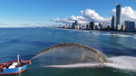 a dredging vessel pumps sand into the ocean near gold coast, australia, under clear skies and bright daylight