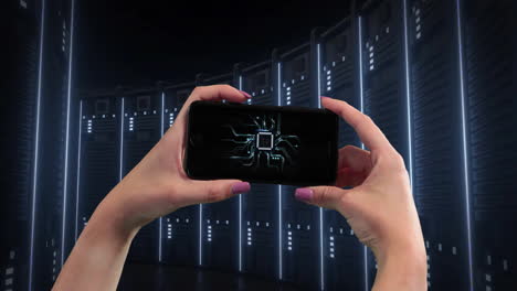 holding smartphone with circuit board animation, person standing in server room