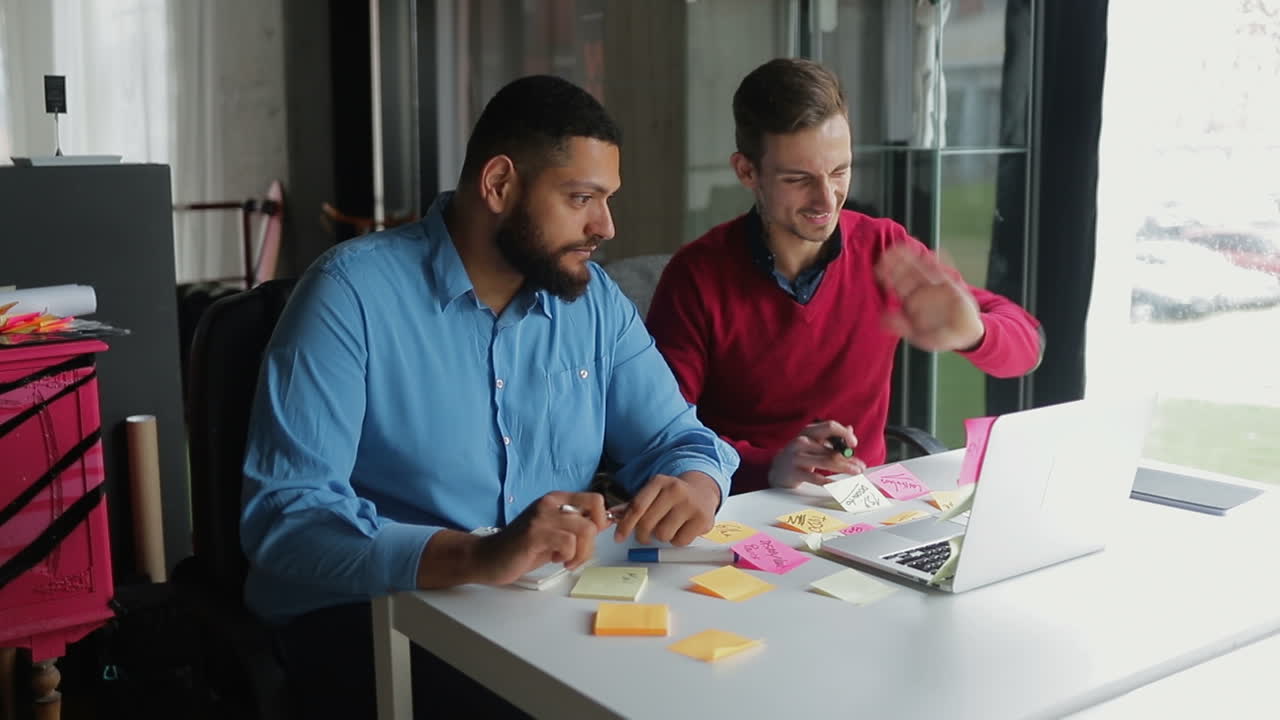 Two young managers having conference through laptop.