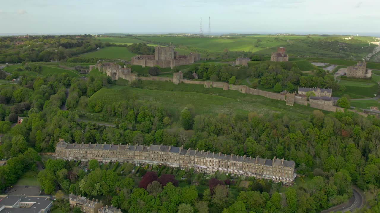 Drone aerial footage of Dover Castle and nearby buildings with green hills, capturing coastal views and historical architecture
