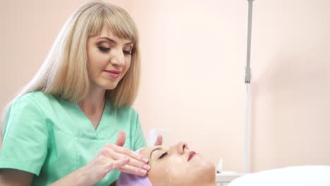 spa day of beautiful woman. beautiful woman relaxing with closed eyes during professional facial massage for rejuvenation