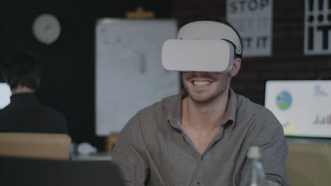 Lachender-Mann,-Der-Sich-Im-Dunklen-Büro-Ein-Video-In-Einer-Virtual-Reality-Brille-Ansieht.