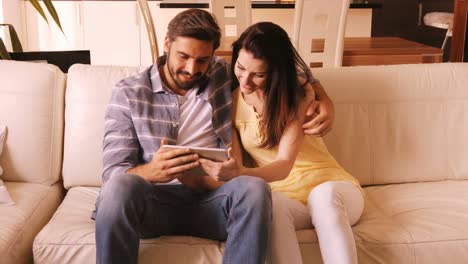pareja relajándose en el sofá y usando una tableta digital