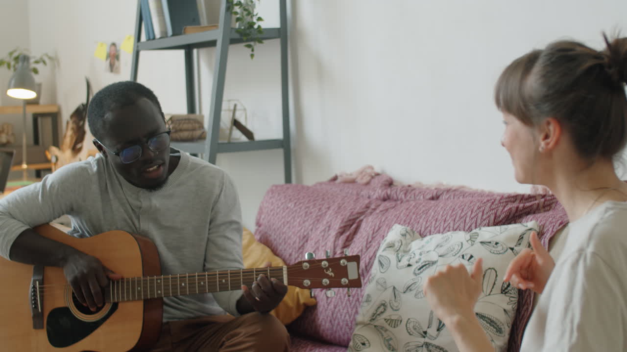 African Man Playing Guitar and Singing for Wife at Home