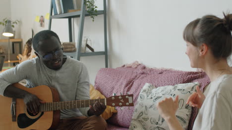 Hombre-Africano-Tocando-La-Guitarra-Y-Cantando-Para-Su-Esposa-En-Casa