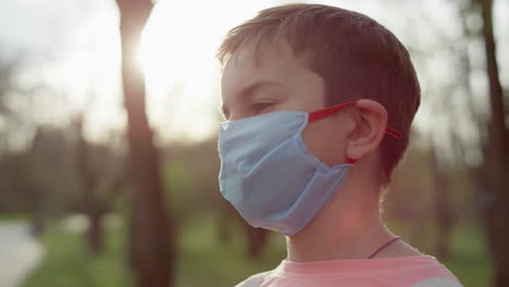 Serious-guy-standing-in-medical-mask-at-outdoors.-Teenager-boy-taking-away-mask