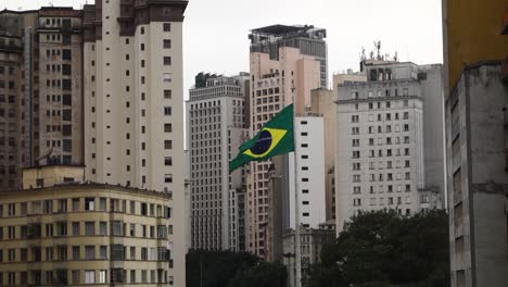 sao paulo, brasilien: brasilianische flagge weht zwischen gebäuden in der innenstadt