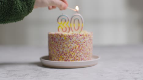 studio shot birthday cake covered with decorations and candle celebrating thirtieth birthday being lit