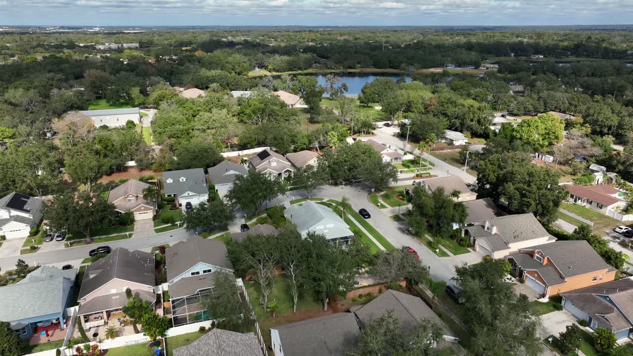 Vista aérea de un barrio residencial de lujo en Brandon, Florida. Calles arboladas, casas modernas y un lago cercano en condiciones de luz diurna clara. Plano general. Zona residencial de lujo de EE. UU.