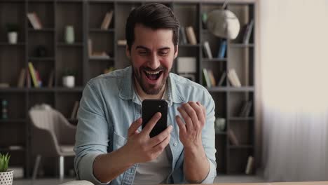 excited man holding smartphone feels happy by great sms news