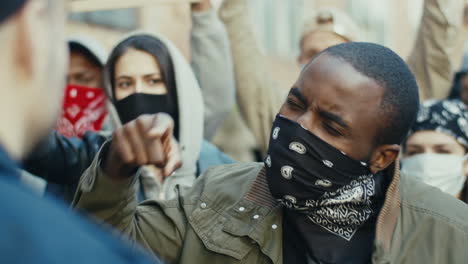 close-up view of african american man yelling at a police officer in a protest with multiethnic group of people in the street