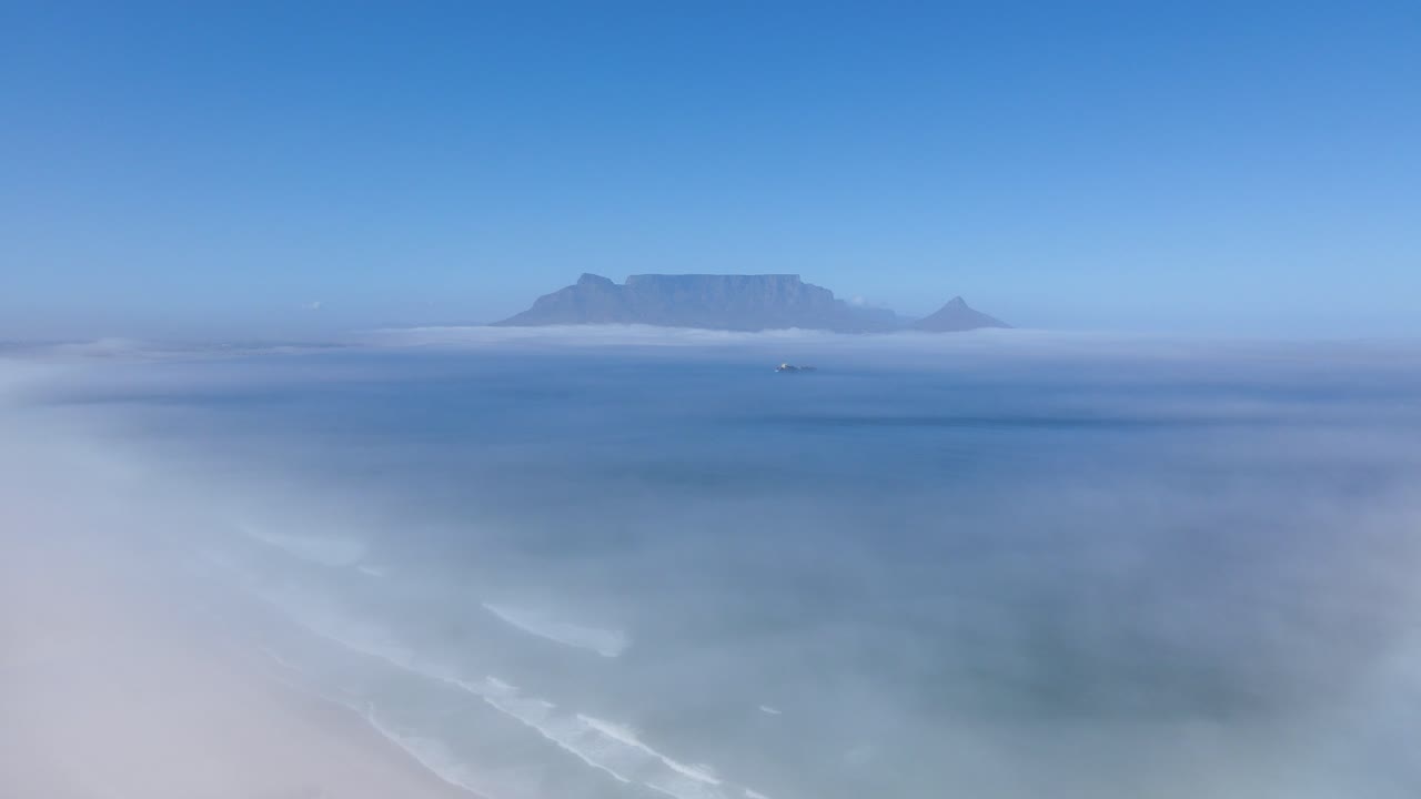 안개 낀 바다 한가운데 떠 있는 배와 배경에 산