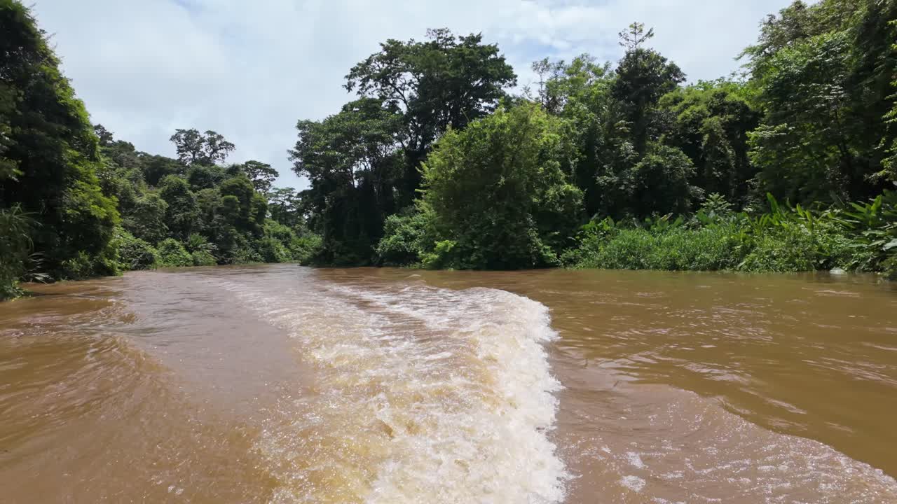 Serene view of Tortuguero's river surrounded by lush rainforest under a cloudy sky in Costa Rica