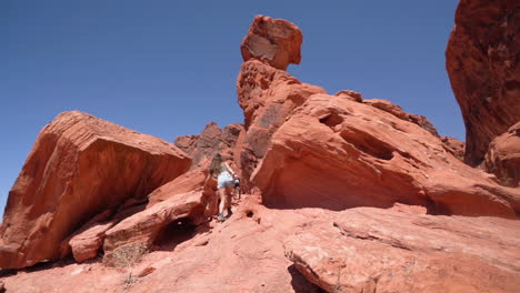 Back-of-Young-Woman-Walking-Under-Red-Rock-Formations,-Valley-of-Fire-State-Park-Nevada-USA