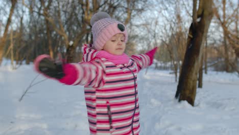 Smiling-child-kid-walking,-having-fun,-relaxing,-looking-around-on-snowy-road-in-winter-park-forest