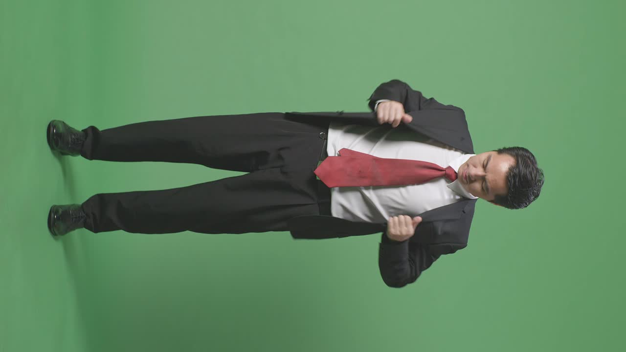 비즈니스맨이 그린 스크린 앞에서 타이를 조정하고 있습니다.