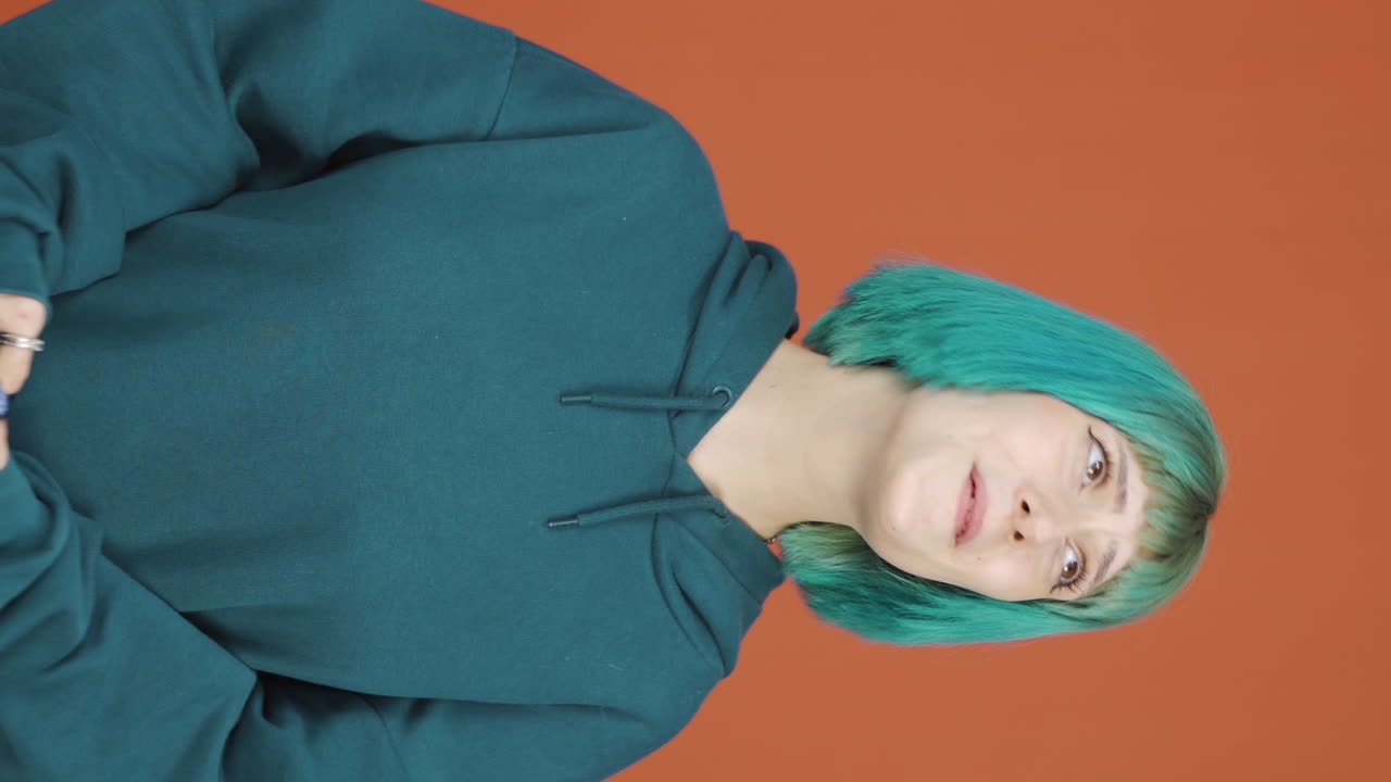 젊은 여성의 수직 비디오는 행복하게 그녀의 심장에 전화를 넣습니다.