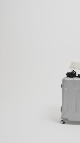 vertical video of suitcase, sunglasses and sunhat with copy space on white background