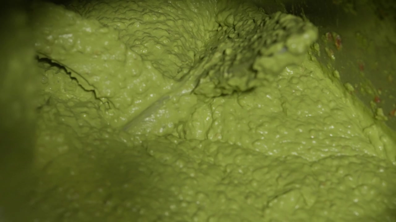 Pasta densa di avocado dalla consistenza liscia che riempie la struttura durante la fase di lavorazione alimentare.
