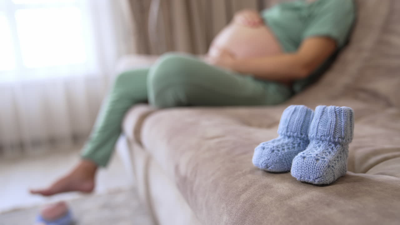 Woman holds baby in pregnant belly. Happy young expecting mother holding baby in pregnant belly