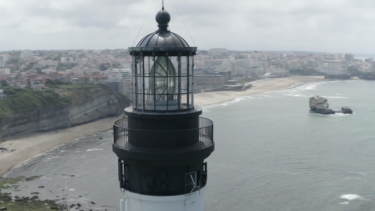 Close-up of Biarritz Lighthouse lamp room, orbiting view, cityscape, beach, Atlantic coast. France. Aerial drone orbiting