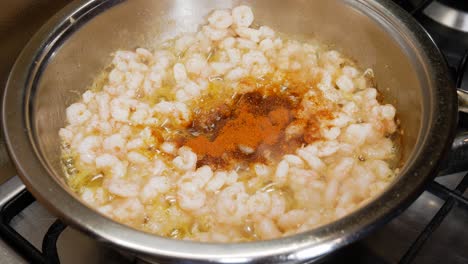 mixing small fresh shrimps with bell pepper powder in steaming hot pot