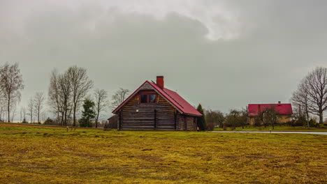 Storm-clouds-roll-in-above-log-cabin-style-home-in-countryside,-Timelapse