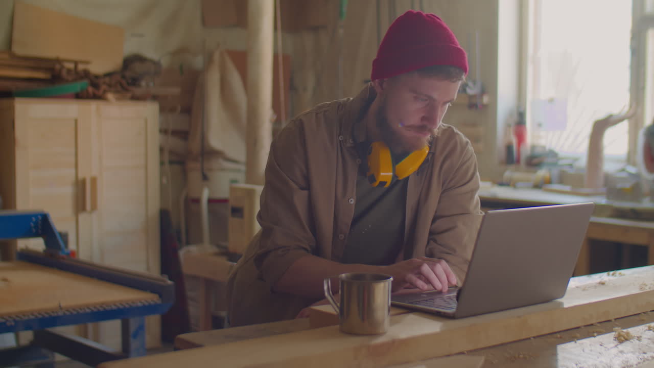 Woodworker Browsing the Web on Laptop in Workshop