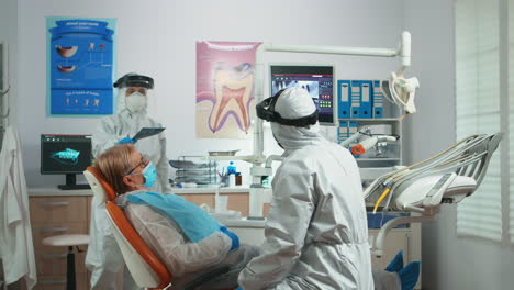 stomatologist in coverall looking at dental x-ray plate