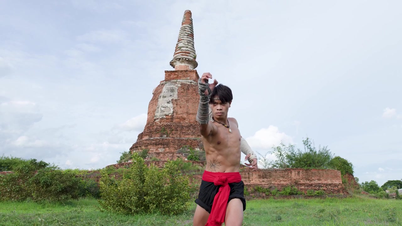 Un luchador tailandés tradicional realiza golpes de artes marciales frente a una antigua pagoda en Ayutthaya, Tailandia.
