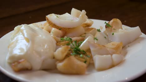 tender grilled squid from a galician taberna, served on a white plate with a drizzle of olive oil and a sprinkle of fresh parsley