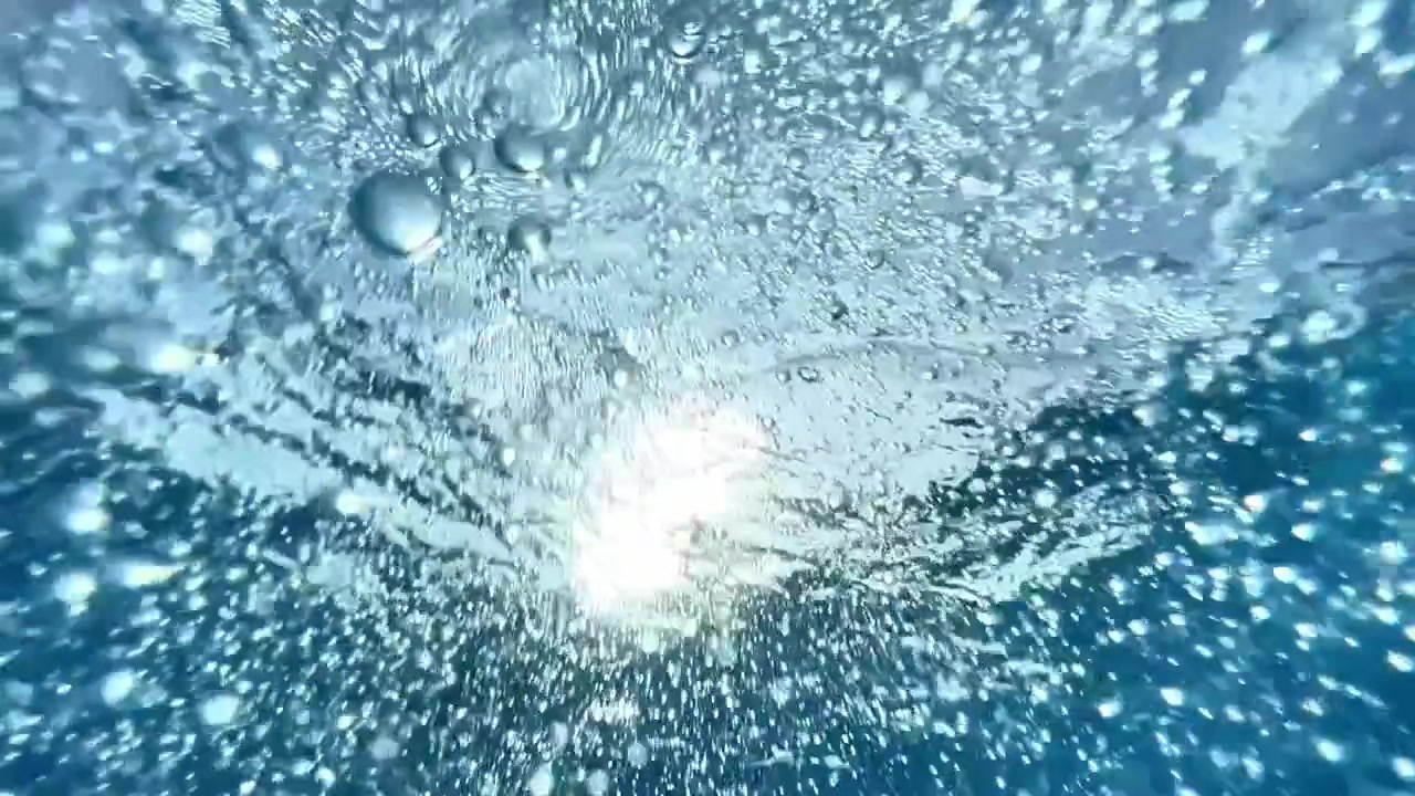 Underwater shot looking up at air bubbles floating toward the surface as sunlight refracts through blue water. Ideal for beverage commercials, wellness campaigns, and travel ads.