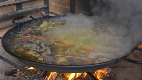 cooking paella on an open fire with smoke