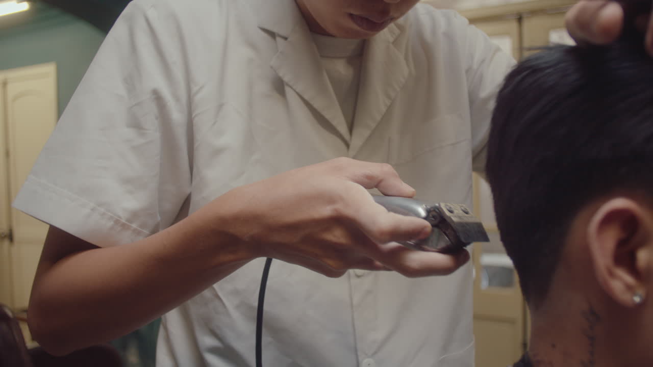 Asian Barber Trimming Hair of Client with Hair Clippers