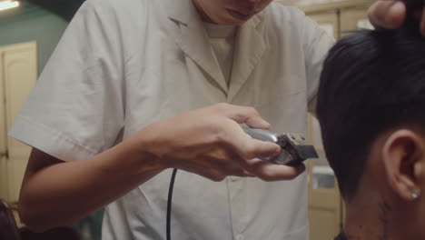 asian barber trimming hair of client with hair clippers
