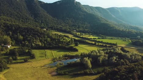 Impressive-aerial-views-of-green-forests-between-mountains,-with-a-beautiful-lake-adding-serenity-to-the-tranquil-beauty-of-the-landscape