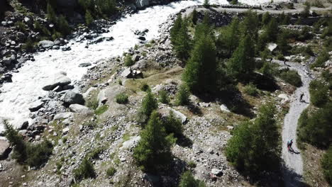 Arroyo-De-Montaña,-Camino-De-Grava-Y-Bosque-De-Abetos,-Vista-Aérea-De-Drones-En-Los-Alpes-Suizos