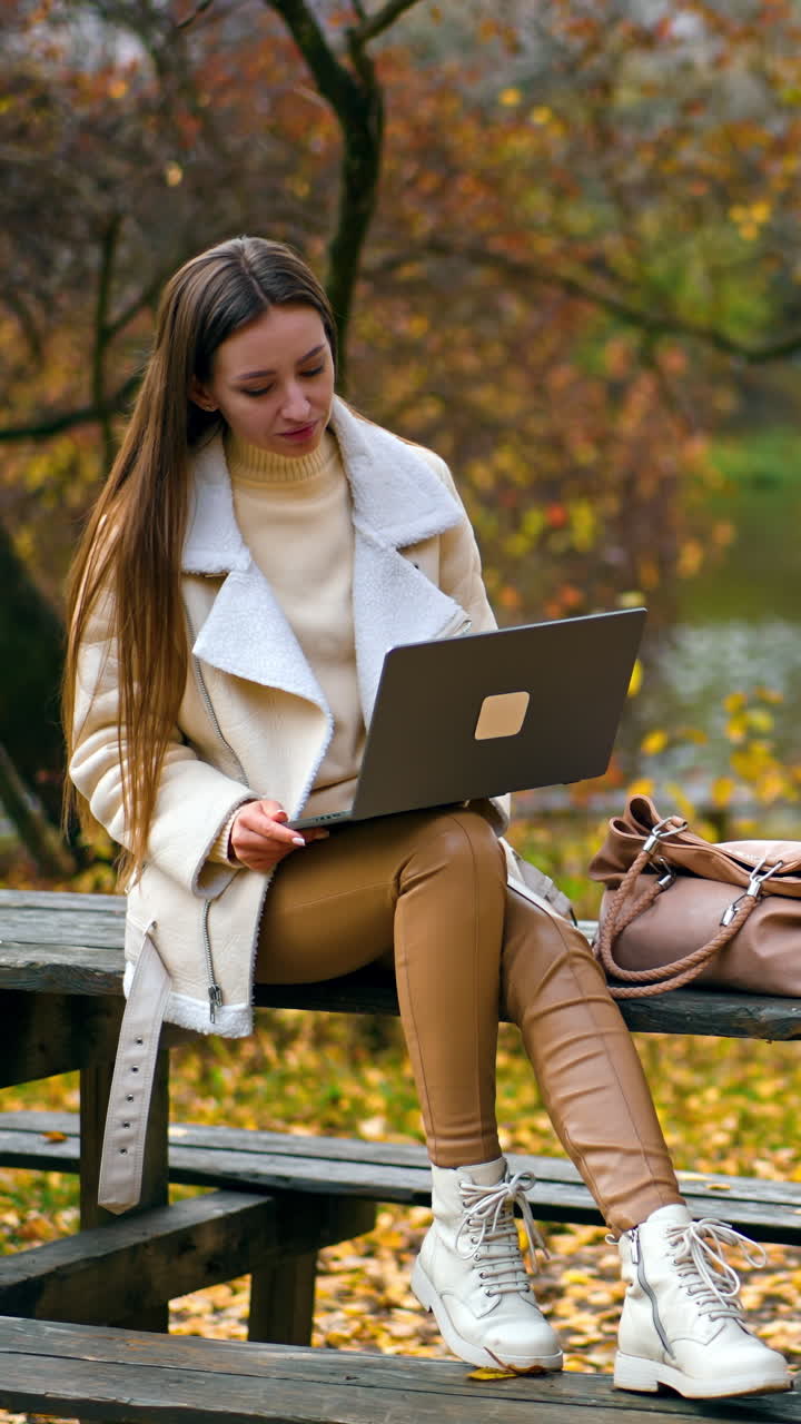 Freelance charming lady have distance work. Young attractive woman working in park with laptop. Vertical video