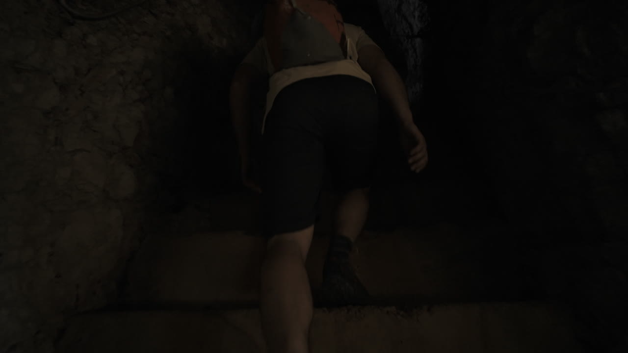 caminante con una mochila caminando en el túnel tallado en la roca y comienza a subir las escaleras también talladas en la roca