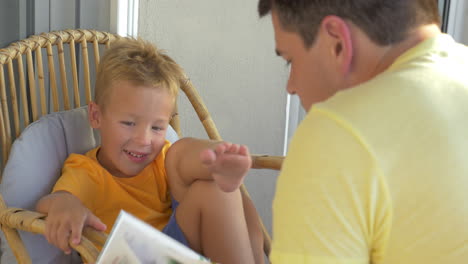 smiling boy listening his father reading a book